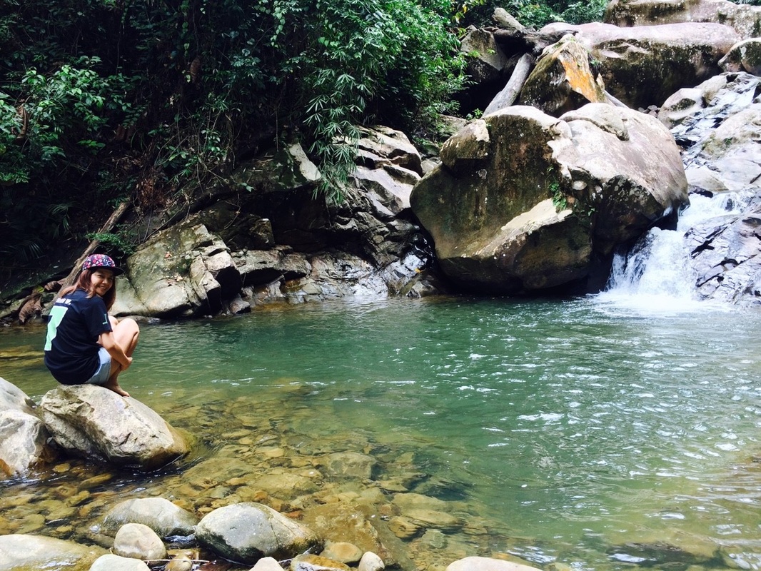 Person relaxing by a serene jungle stream in Borneo.